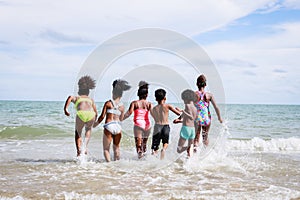 African American, Kids group in swimwear enjoying running to play the waves on beach. Ethnically diverse concept. Having fun after