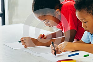 African American kids learning how to draw with crayon on table photo