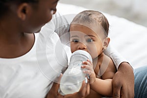 African American lady feeding her child from baby bottle