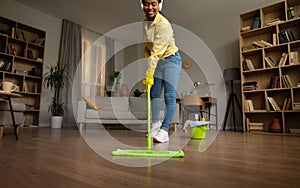 African American Lady Mopping Floor Wearing Earphones Cleaning House Indoors