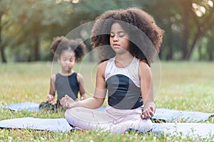 African American little girl sitting on the roll mat practicing meditate yoga in the park outdoor