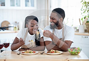 African American Lovers Eating Spaghetti And Drinking Red Wine In Kitchen