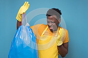 African american male in apron and gloves holding a stinky garbage bag