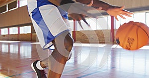 African american male basketball player practicing dribbling ball