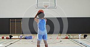 African american male basketball player shooting ball at hoop, training at indoor court, slow motion