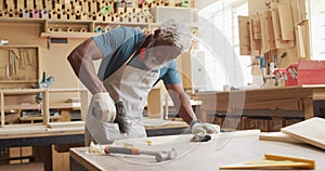 African american male carpenter drilling holes in wooden plank using hand drilling machine