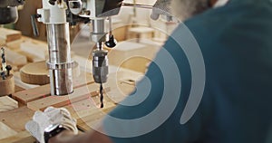 African american male carpenter drilling wood with a laser drill in a carpentry shop