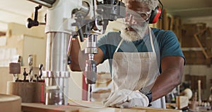 African american male carpenter drilling wood with a laser drill in a carpentry shop