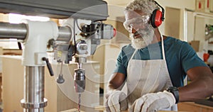 African american male carpenter drilling wood with a laser drill in a carpentry shop