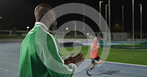 African american male coach clapping watching disabled male athlete with running blade training