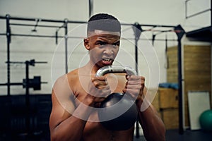 African American male doing cross fit in gym. Mixed race male using a kettlebell during exercise. High quality photo