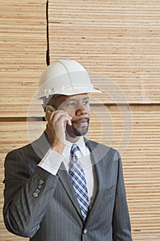 African American male engineer on phone call with stacked wooden planks in background