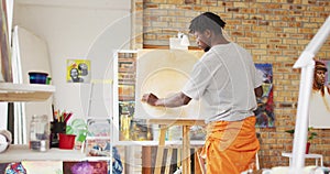 African american male painter painting on canvas in artist studio