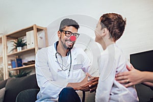 African American male pediatrician with stethoscope and clown nose talking to boy