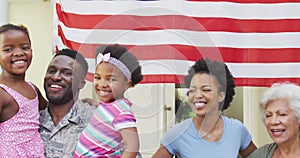 African american male soldier embracing his smiling family over american flag