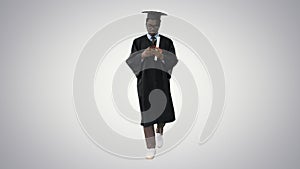 African american male student in graduation robe texting on the