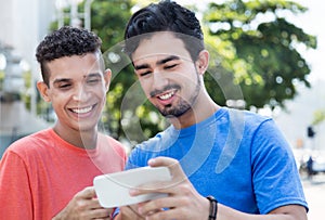African american male student with typical hairstyle in cityTwo hispanic guys showing pictures on phone