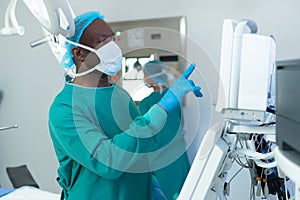 African american male surgeon operating computerised medical equipment in operating theatre