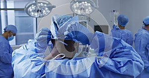 African american male surgeon putting on protective clothes standing in operating theatre