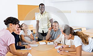 African american male teacher, together with students of different ages, conducts intensive classes at round table in