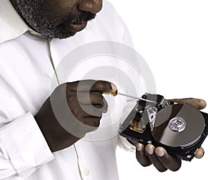 African American Male technician hand holding and working on  computer hard drive with screwdriver