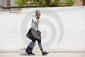 African american male traveler walking outside and talking on cell phone