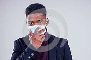 African american male wearing on a gauze mask and warm coat and sweater white background studio. cold season winter