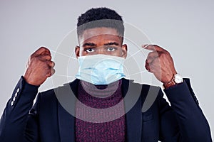 African american male wearing on a gauze mask and warm coat and sweater white background studio. cold season winter