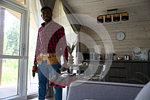 African American male worker in bright room with tools and drill