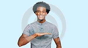 African american man with afro hair wearing casual clothes gesturing with hands showing big and large size sign, measure symbol