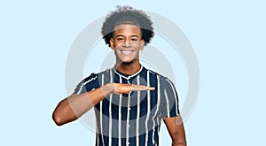 African american man with afro hair wearing casual clothes gesturing with hands showing big and large size sign, measure symbol