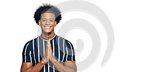 African american man with afro hair wearing casual clothes praying with hands together asking for forgiveness smiling confident