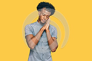 African american man with afro hair wearing casual clothes sleeping tired dreaming and posing with hands together while smiling