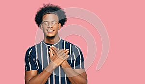 African american man with afro hair wearing casual clothes smiling with hands on chest with closed eyes and grateful gesture on