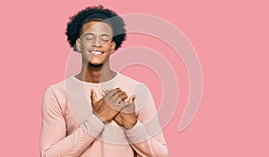 African american man with afro hair wearing casual clothes smiling with hands on chest with closed eyes and grateful gesture on