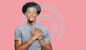 African american man with afro hair wearing casual clothes smiling with hands on chest with closed eyes and grateful gesture on