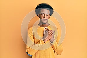 African american man with afro hair wearing casual clothes smiling with hands on chest, eyes closed with grateful gesture on face