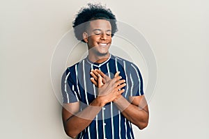 African american man with afro hair wearing casual clothes smiling with hands on chest, eyes closed with grateful gesture on face