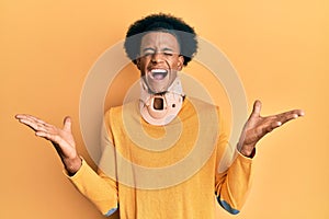 African american man with afro hair wearing cervical neck collar celebrating mad and crazy for success with arms raised and closed