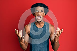 African american man with afro hair wearing sportswear crazy and mad shouting and yelling with aggressive expression and arms