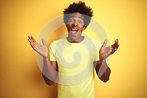 African american man with afro hair wearing t-shirt standing over isolated yellow background celebrating crazy and amazed for