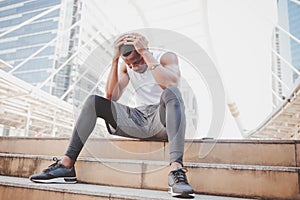 African American man with black skin he is and athlete, He is stressed and headache while he is sitting on the stairs