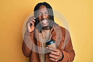 African american man with braids having conversation talking on the smartphone sticking tongue out happy with funny expression