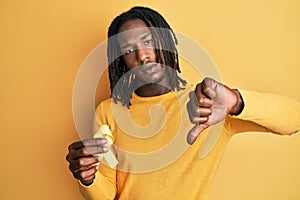 African american man with braids holding suicide prevention yellow ribbon with angry face, negative sign showing dislike with