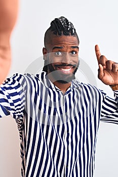 African american man with braids make selfie by camera over isolated white background surprised with an idea or question pointing