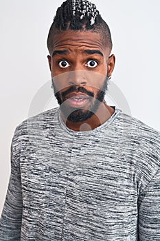 African american man with braids wearing grey sweater over isolated white background scared in shock with a surprise face, afraid