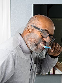 African American Man brushing teeth in bathroom.  Dental health care using toothbrush and tooth paste