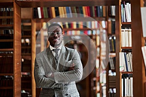 An African American man in a business suit standing in a library in the reading room.