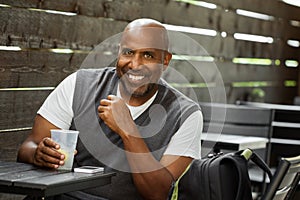 African American man at a cafe drinking and texting.
