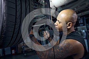 African American man checking tightness and reliability of nuts on car wheels